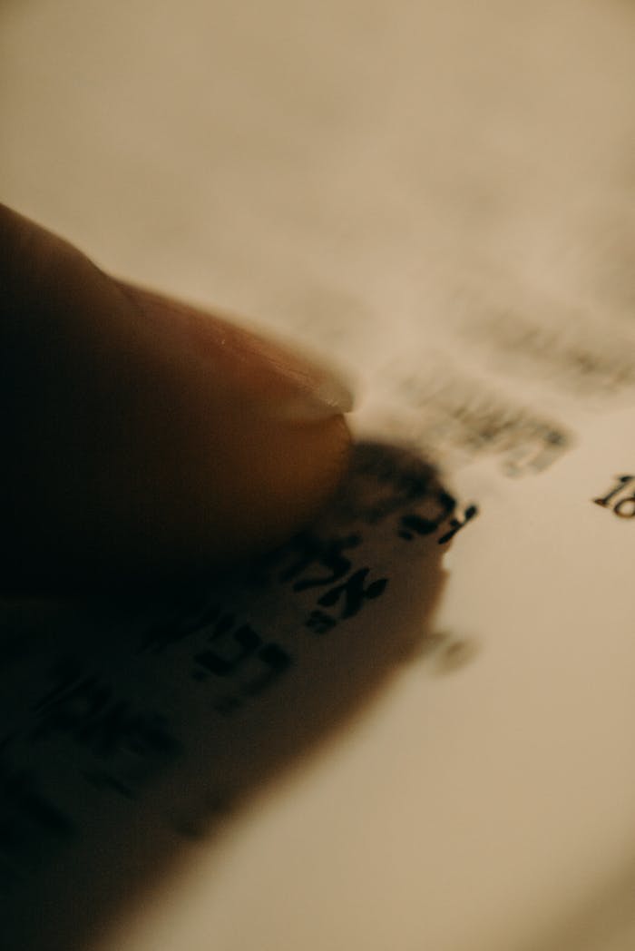 Close-up of a finger tracing Hebrew text in an open book, capturing detail and tradition.